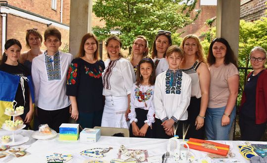 Photographs showing multiple families in front of a food stand at Refugee Week 2023 at Amersham