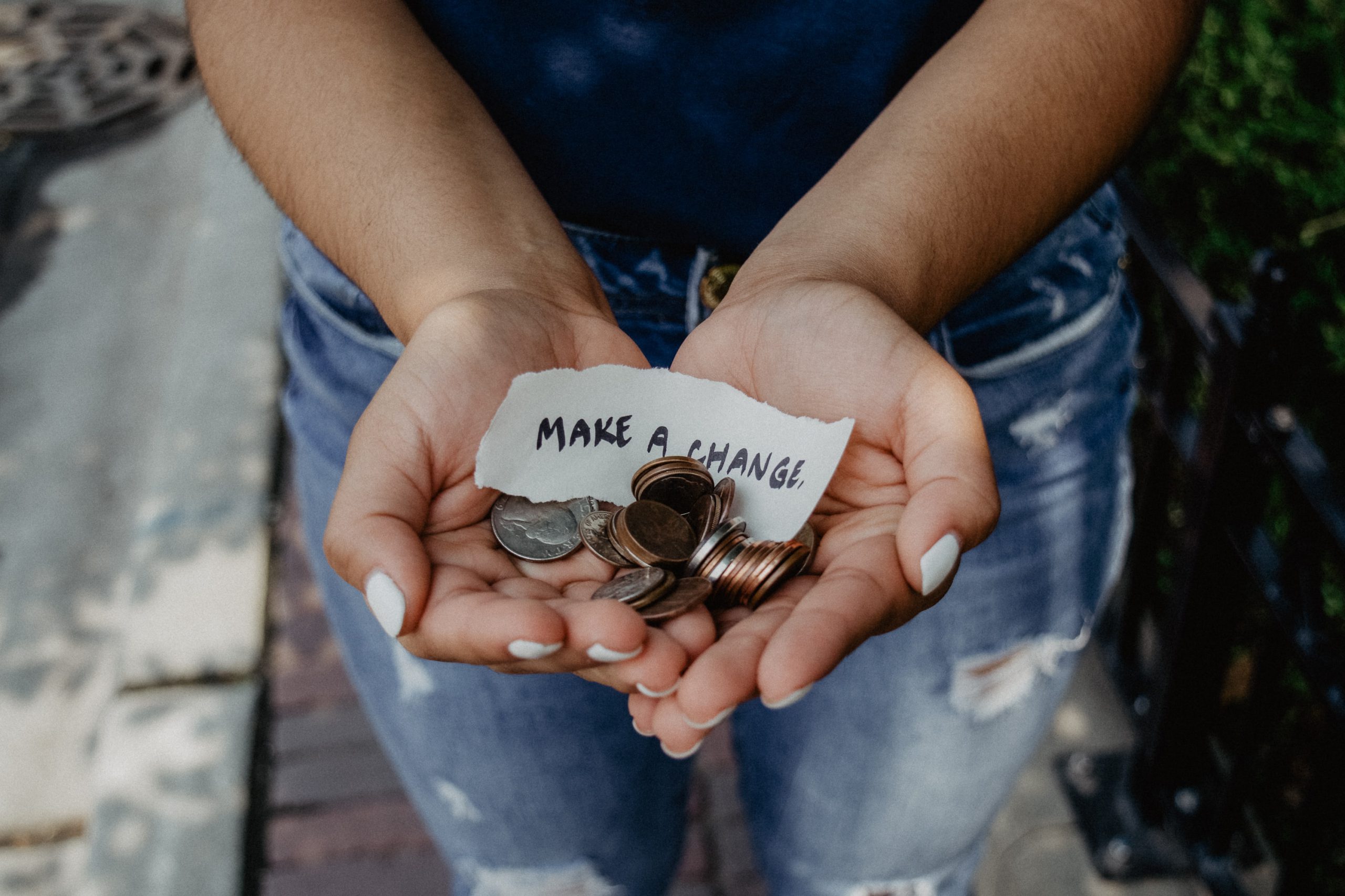 Photograph showing two hands with coins and a note 'Make a change'