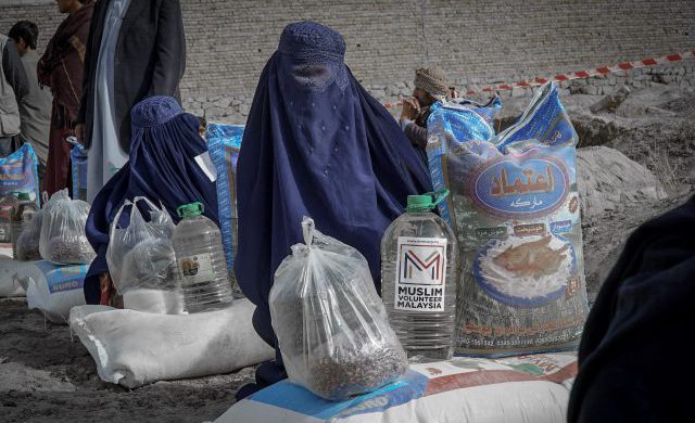 Photograph of Afganistan showing a woman with water bottle and food bags